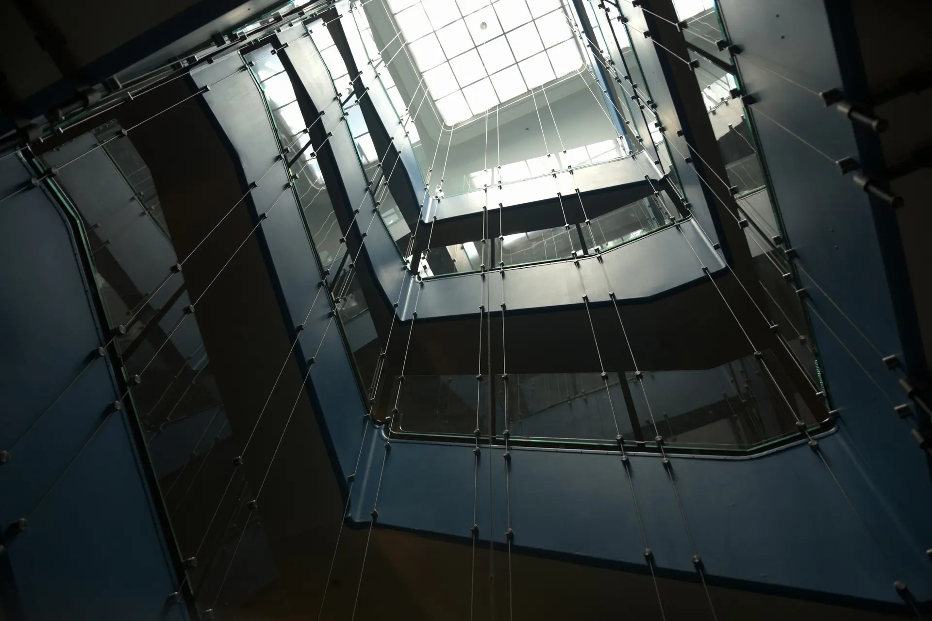 Low-angle view looking up through the levels of a building toward a glass ceiling, representing a business growth ceiling
